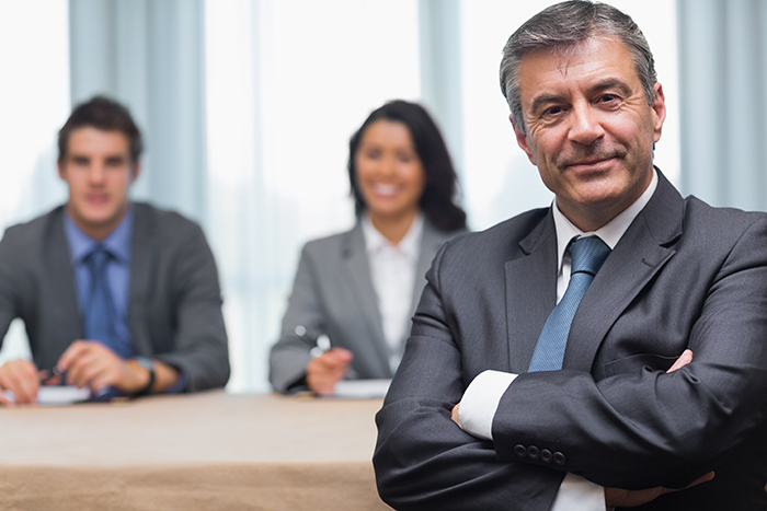 Businessman with arms crossed sitting with business panel in conference room