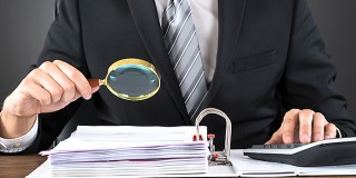 Businessman Inspecting Invoice With Magnifying Glass