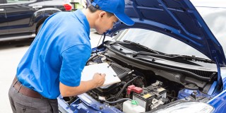 Mechanic man holding clipboard and check the car